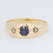 An 18ct yellow gold 'gypsy' style ring set with a central round cut sapphire and two small round cut