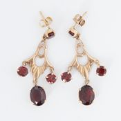 A pair of ornate 9ct yellow gold drop earrings set with oval & round cut garnets, measuring