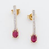A pair of 18ct yellow gold drop earrings each set with an oval cut ruby & small round brilliant