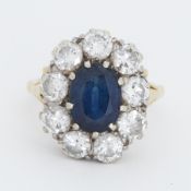 An 18ct yellow & white gold cluster ring set with a central oval cut sapphire, approx. 2.14