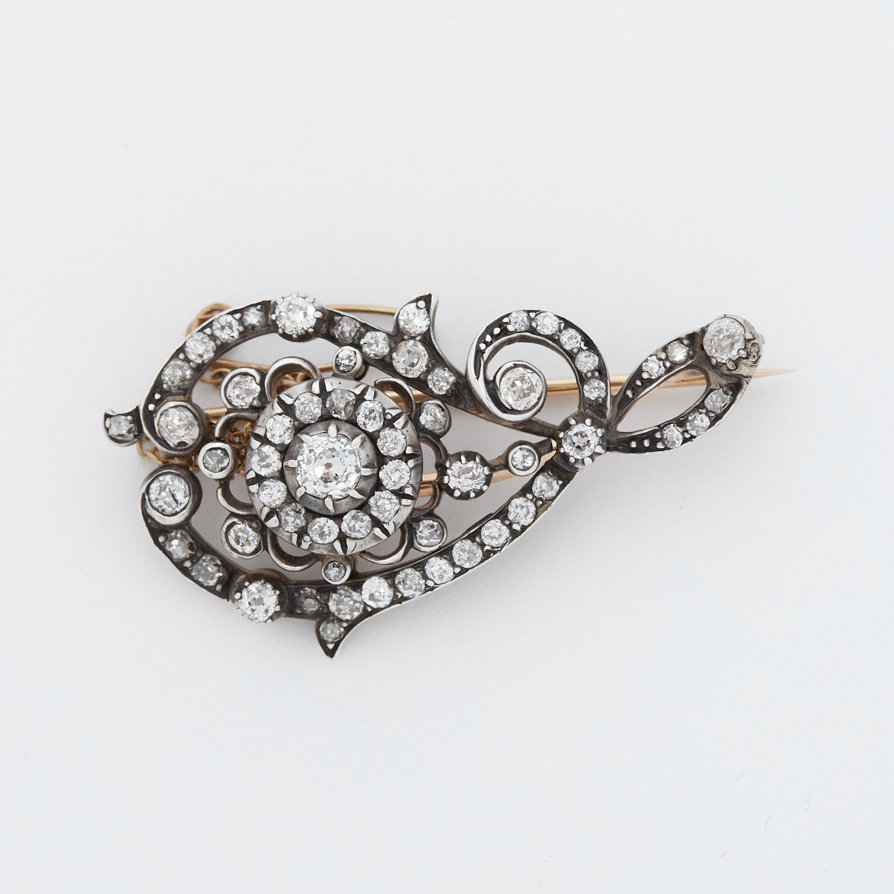 A Victorian 'scroll' design brooch set with old round cut diamonds, the largest diamond is approx.