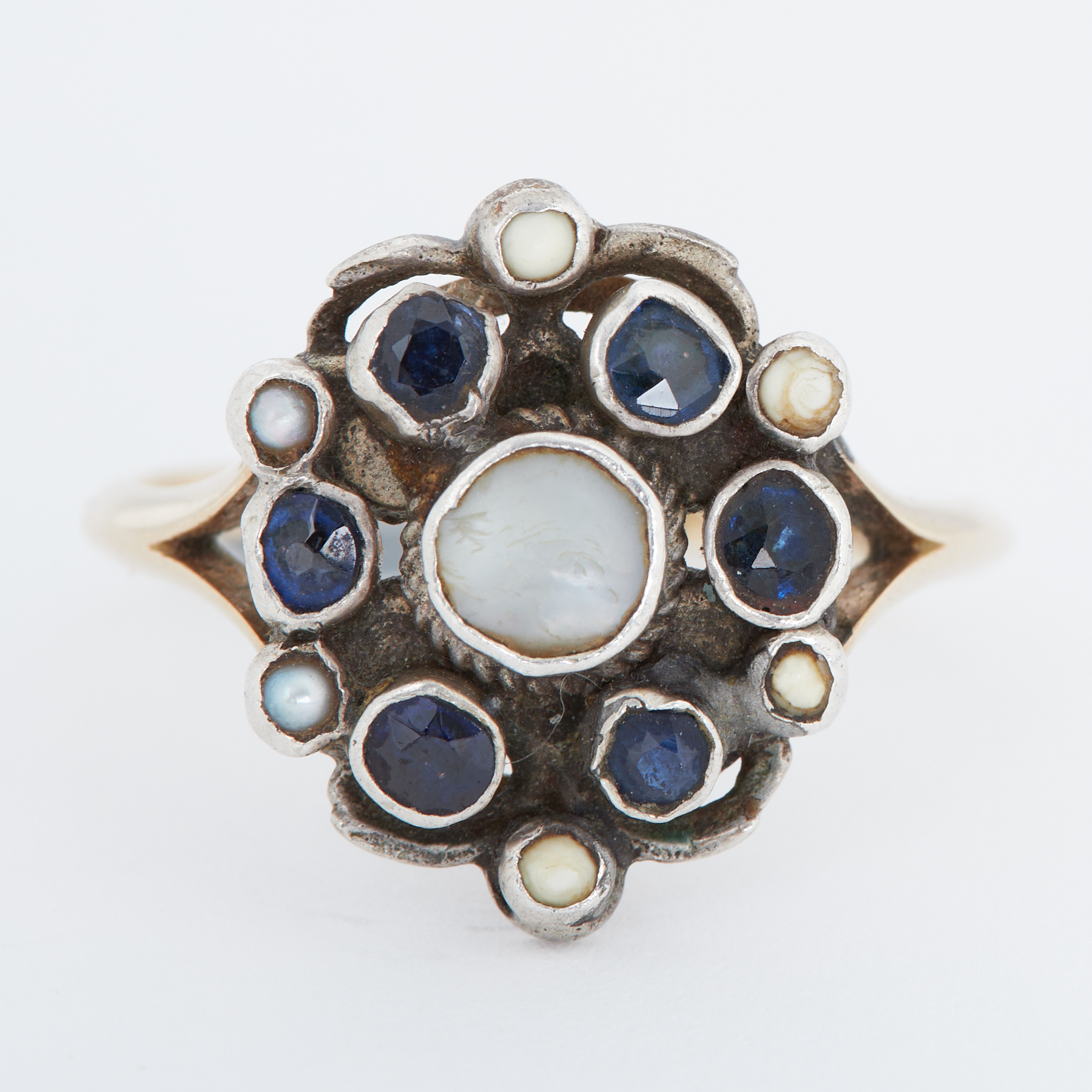 An Arts & Crafts yellow gold & white metal ring set with small round cut sapphires & pearls, the