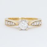 An 18ct yellow gold ring set with a central round brilliant cut diamond and graduated round