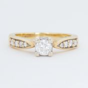 An 18ct yellow gold ring set with a central round brilliant cut diamond and graduated round