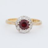 An 18ct yellow & white gold cluster ring set with a central round cut garnet surrounded by small