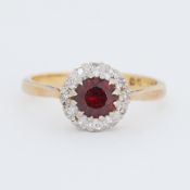 An 18ct yellow & white gold cluster ring set with a central round cut garnet surrounded by small
