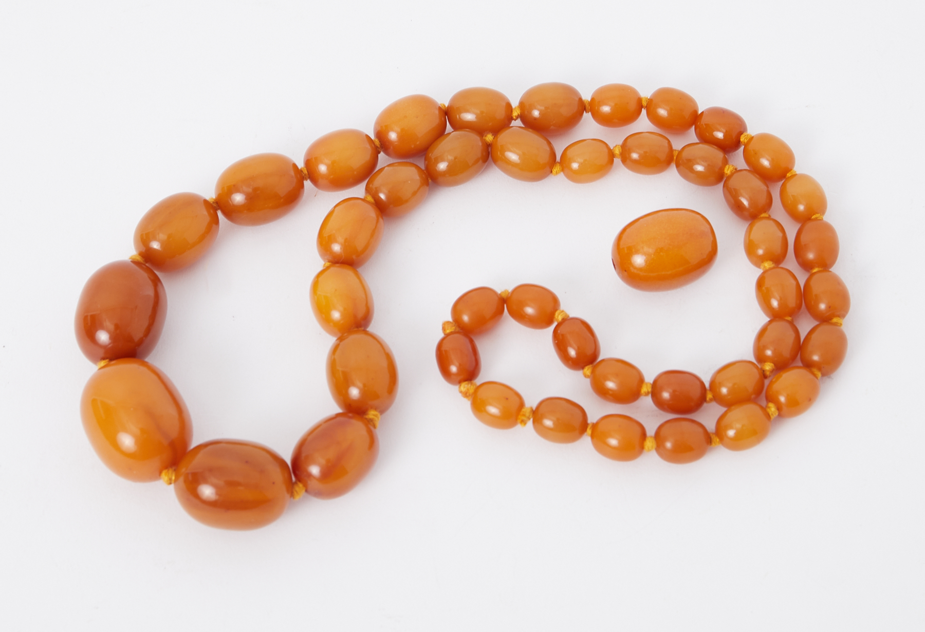 A 24" string of oval butterscotch amber beads and one loose oval butterscotch amber bead, total