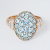 A 9ct yellow gold oval design ring set with round cut blue topaz and two small round cut diamonds