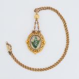 A Victorian pinchbeck Etruscan style pendant set centrally with an oval glass panel with raised lily