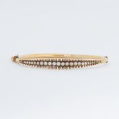 A 15ct yellow gold antique bangle set with seed pearls, safety chain