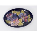 Moorcroft oval dish decorated with blue/purple flowers, 23cm diameter.