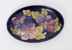 Moorcroft oval dish decorated with blue/purple flowers, 23cm diameter.