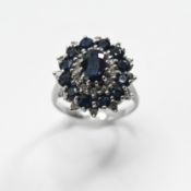An 18ct white gold cluster ring set with a central oval cut sapphire, surrounded by round cut