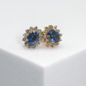 A pair of 14ct yellow & white gold cluster earrings set centrally with an oval cut sapphire, total