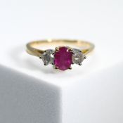 An 18ct yellow & white gold three stone ring set with a central oval cut ruby, approx. 0.37