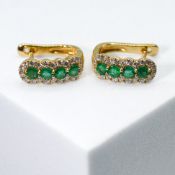 A pair of 18ct yellow gold 'huggie' style earring each set with four round cut emeralds, total