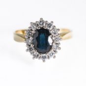An 18ct yellow gold cluster ring set with a central oval cut dark blue sapphire, approx. 1.06