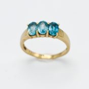 A 9ct yellow gold and three stone blue Topaz ring, size N.