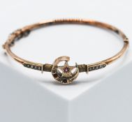 An antique 9ct rose gold bangle with a central moon & star design set with seed pearls, three old