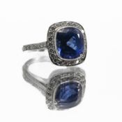 A platinum square design cluster ring set centrally with a rounded square cut tanzanite, approx. 4.