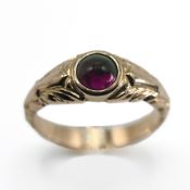 A 14ct yellow gold ring set with a round cabochon cut amethyst, approx. 5.5mm diameter, ornately