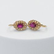 A pair of yellow gold cluster style earrings set with a central oval cut ruby, approx. total ruby