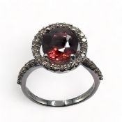 A 14ct white gold modern cluster style ring set with an oval cut pink tourmaline, approx. 3.70