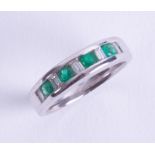 An 18ct white gold half eternity style ring set with four round cut emeralds