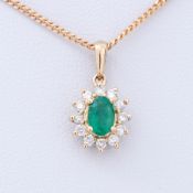 A 9ct yellow gold cluster design pendant set with a central oval cut emerald