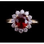 An 18ct yellow gold cluster ring set with a central oval cut orange garnet
