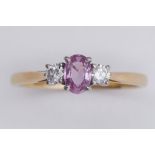 An 18ct yellow & white gold three stone ring set with a central oval cut pink sapphire