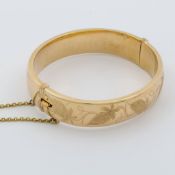 A 9ct yellow gold hinged bangle with leaf engraving to the front, Birmingham, 1976