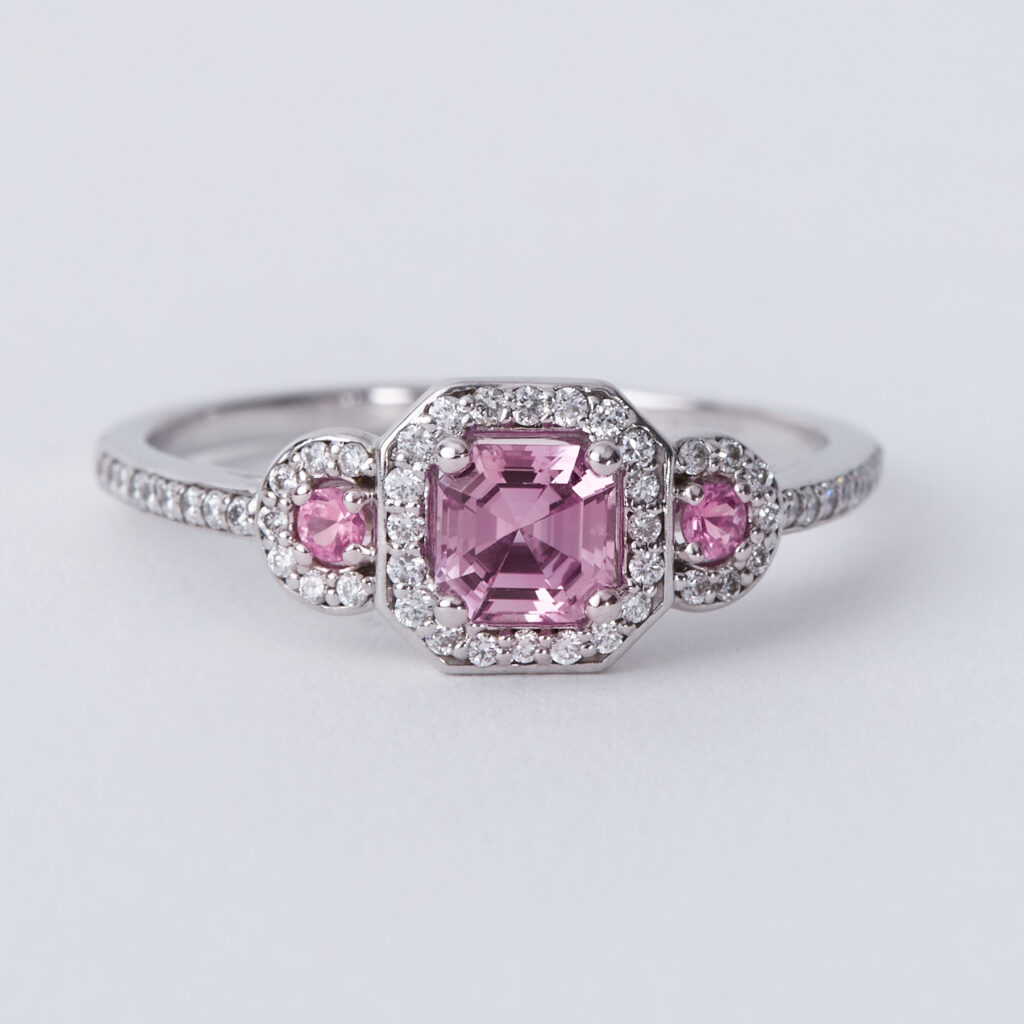 An 18ct white gold ring set with a central pink sapphire with a round pink sapphire to each side