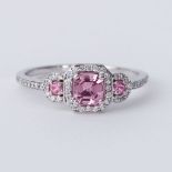 An 18ct white gold ring set with a central pink sapphire with a round pink sapphire to each side