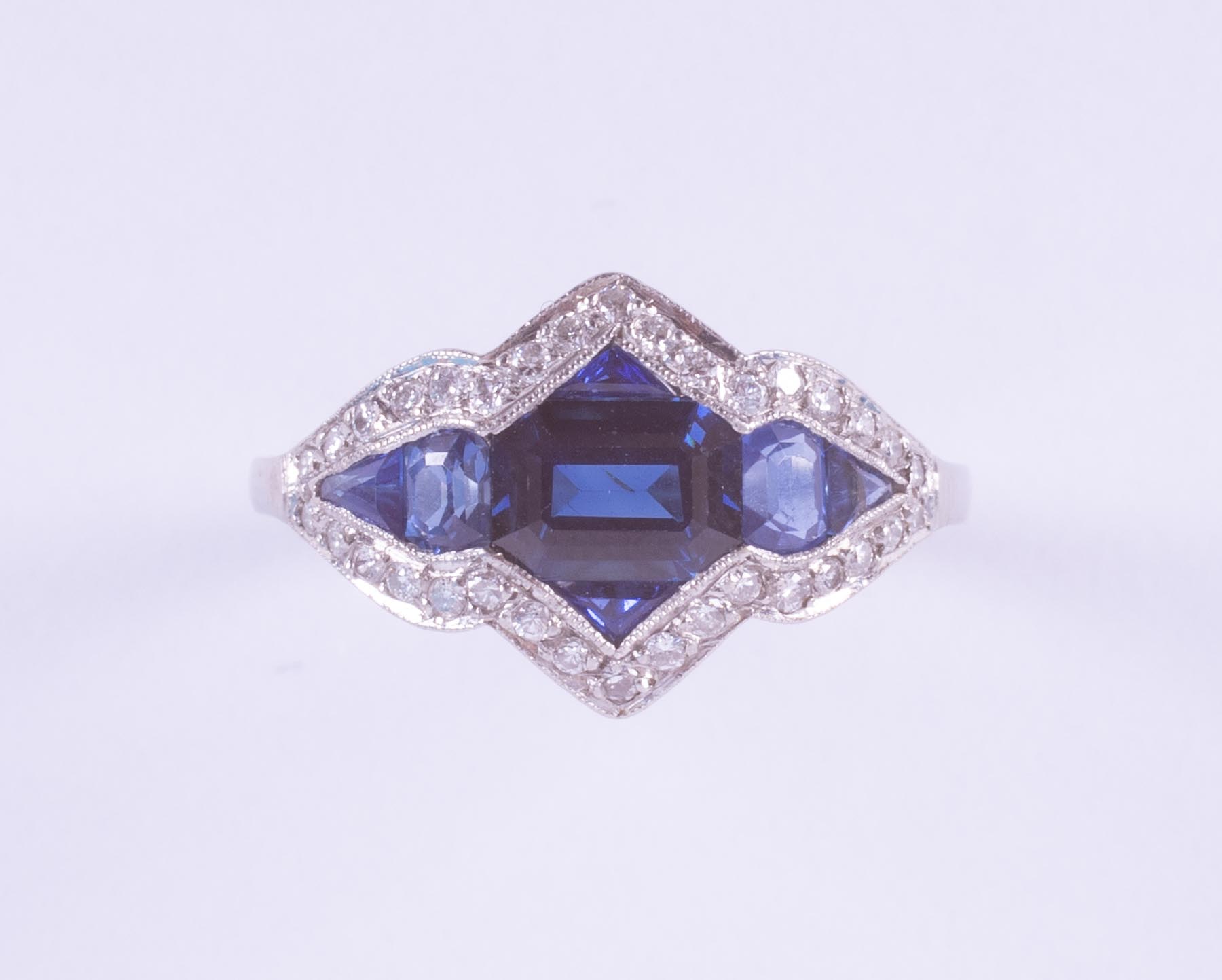 A platinum Art Deco ring (no hallmarks) set with a central emerald cut sapphire