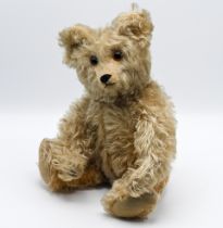 A vintage teddy bear possibly English with hump back, long limbs, amber and black glass eyes with