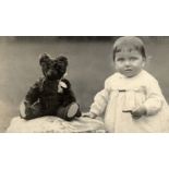 An early 20th century Teddy Bear, originally black, very worn and in poor condition, a photograph