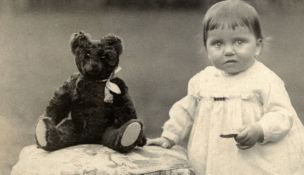 An early 20th century Teddy Bear, originally black, very worn and in poor condition, a photograph
