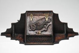 An oak hanging corner cupboard decorated with a carved motif of an owl, 24.5cm.