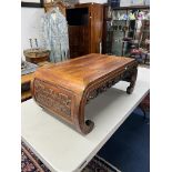 A Chinese hardwood coffee table, carved with the legs forming the scroll ends and the apron carved