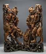 A pair of carved wood figures of Li Tieguai, each with the Daoist Immortal seated astride a mythical