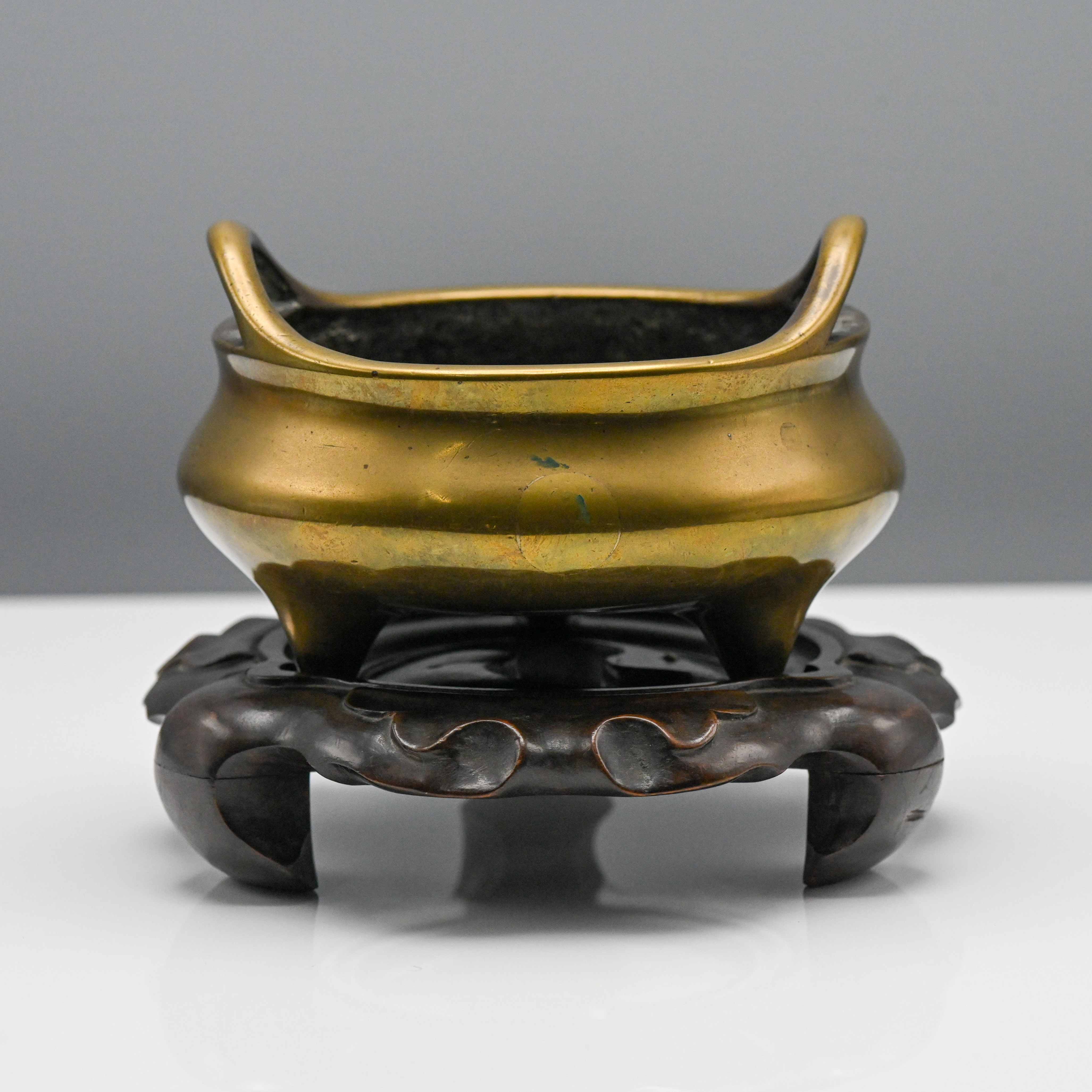 A polished bronze tripod censer, 17th/18th century, the compressed globular body on three short feet