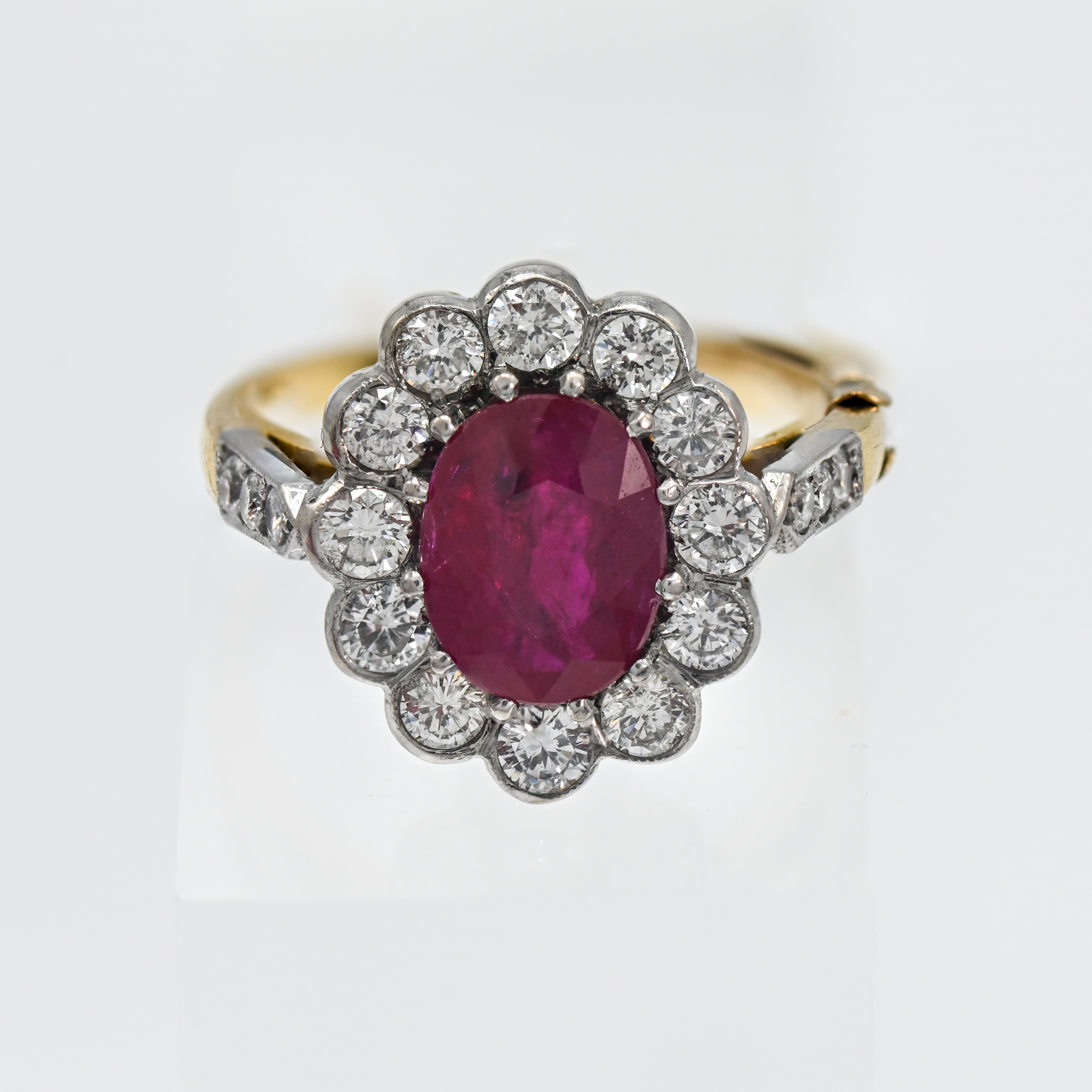 An 18ct yellow gold ruby and diamond cluster ring, set with a centre oval brilliant cut ruby, 12