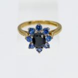 An 18ct yellow gold sapphire cluster ring, set with a central oval cut sapphire surrounded by a