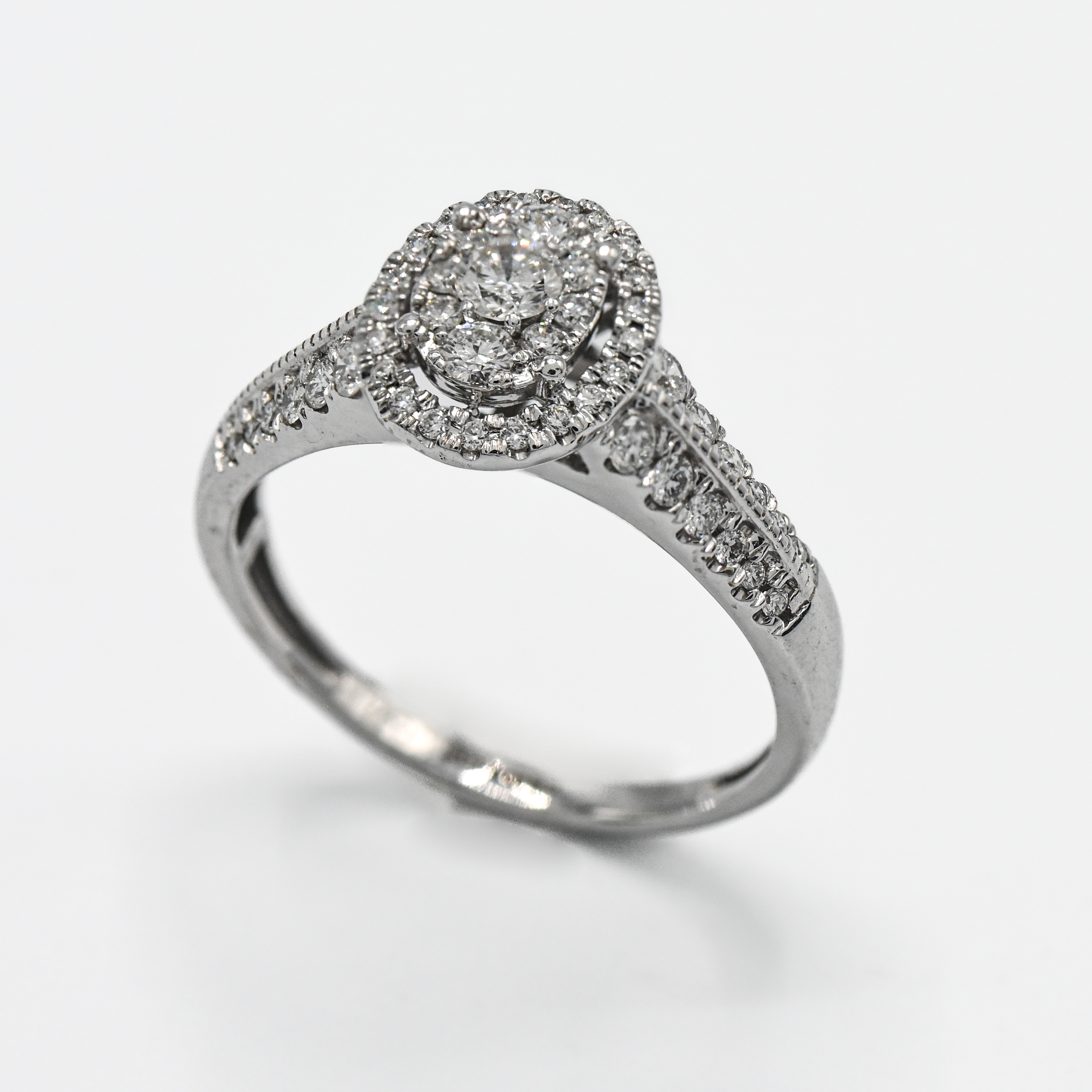 An 18ct white gold oval Pave set diamond cluster ring, set with diamonds on the shoulders, size R.