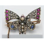 An antique butterfly brooch set with diamonds, ruby's, sapphires and seed pearl.
