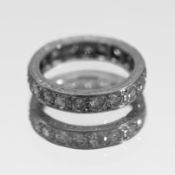 A full band eternity ring, probably platinum, classic stud-claw set with engraved border, size K,