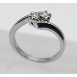 An 18ct white gold two stone diamond cross over ring, size K.