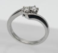An 18ct white gold two stone diamond cross over ring, size K.
