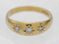 An 18ct yellow gold and diamond three stone set ring of Gypsy style, size X
